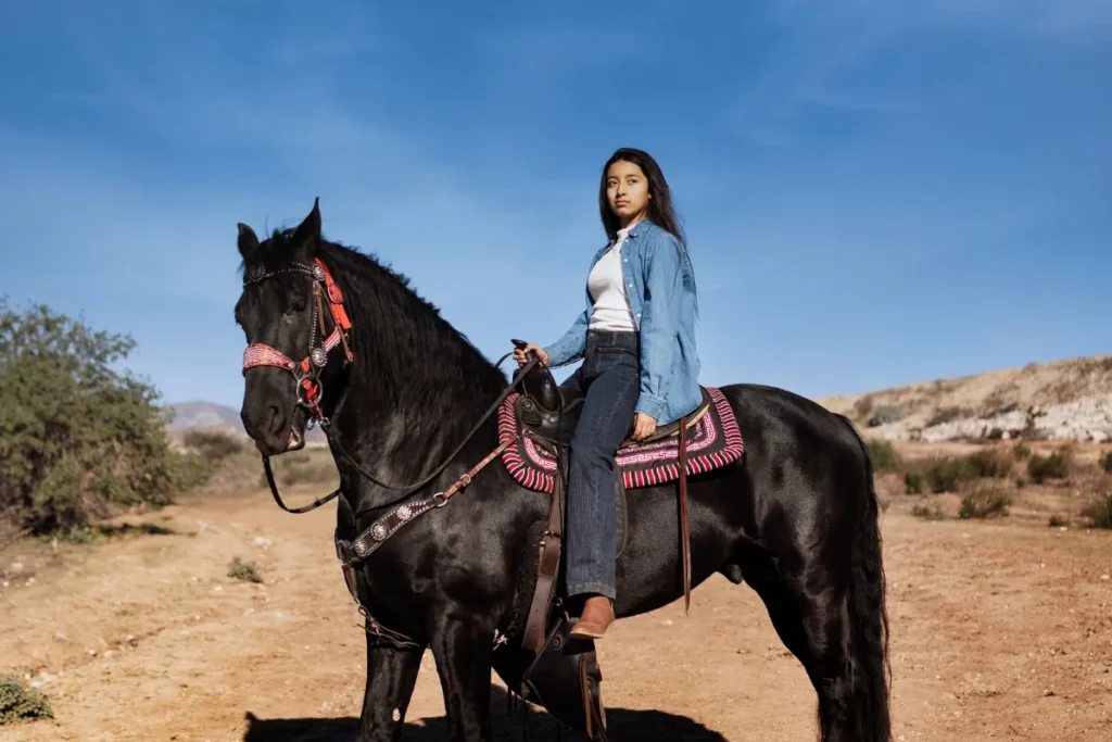 Confident young woman riding a black horse in Agadir – Horse Riding Agadir