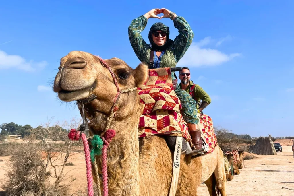 Tourists riding camels dressed in traditional clothing during an agadir camel ride.