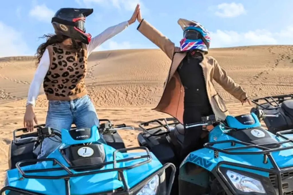 Two women high-fiving during a Quad Agadir desert tour