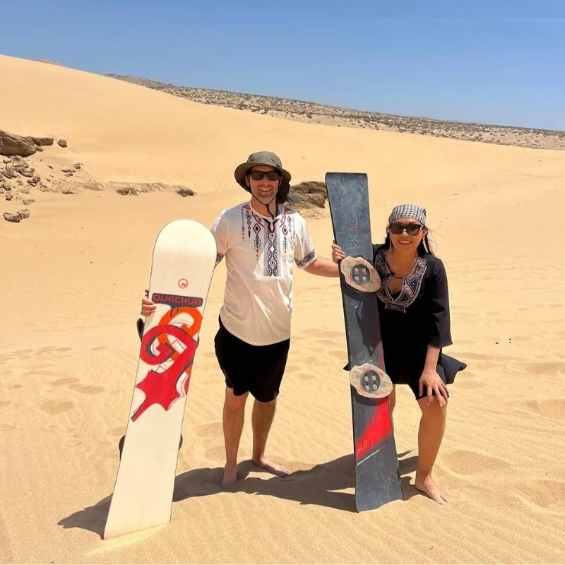 Couple holding sandboards in the desert during sandboarding in Agadir – authentic sandboarding Agadir tour