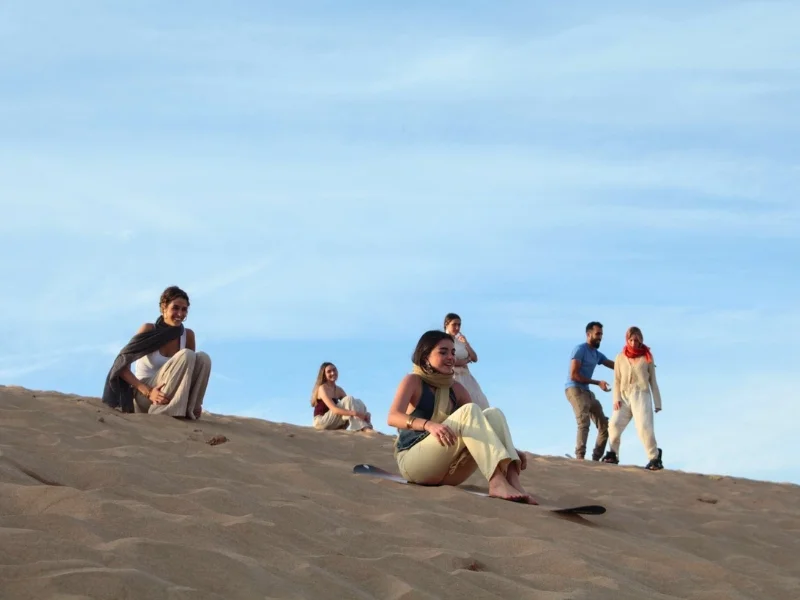 Group of friends enjoying sandboarding in Agadir during sunset – best sandboarding in Agadir for all ages