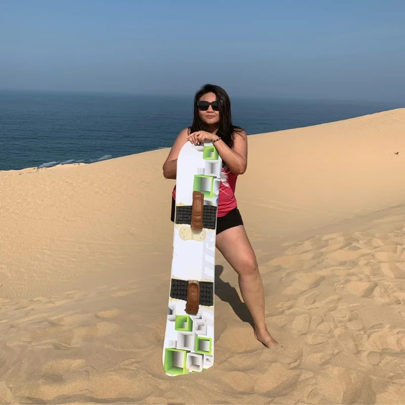 Woman posing with sandboard on golden dunes during sandboarding Agadir tour – sandboarding in Agadir with ocean view