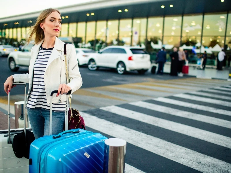 Agadir Airport Transfer – traveler with luggage outside Al Massira Airport crossing pedestrian area