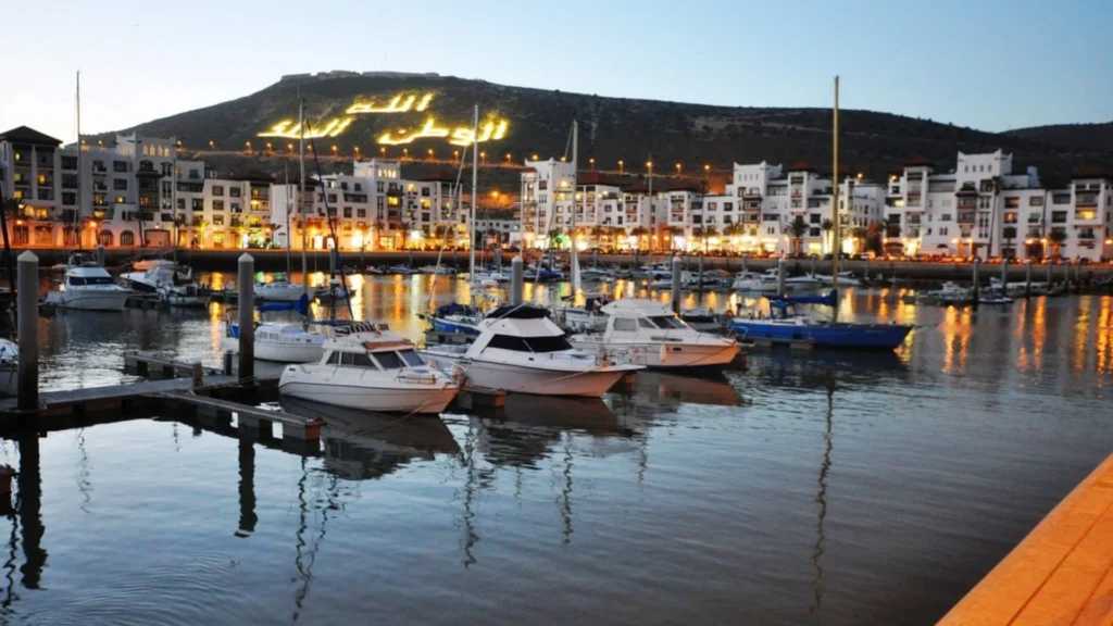 Agadir excursions at the Marina with boats and the illuminated Kasbah hill at sunset