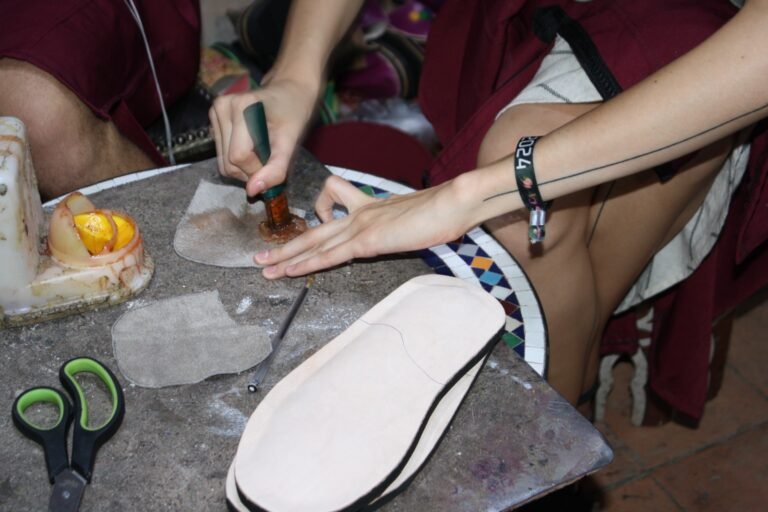 Hands applying glue to leather during a babouche-making workshop in Agadir