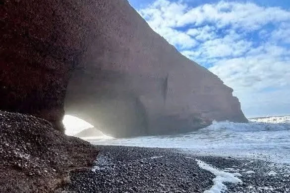 Small natural rock arch on the black pebble beach at Legzira