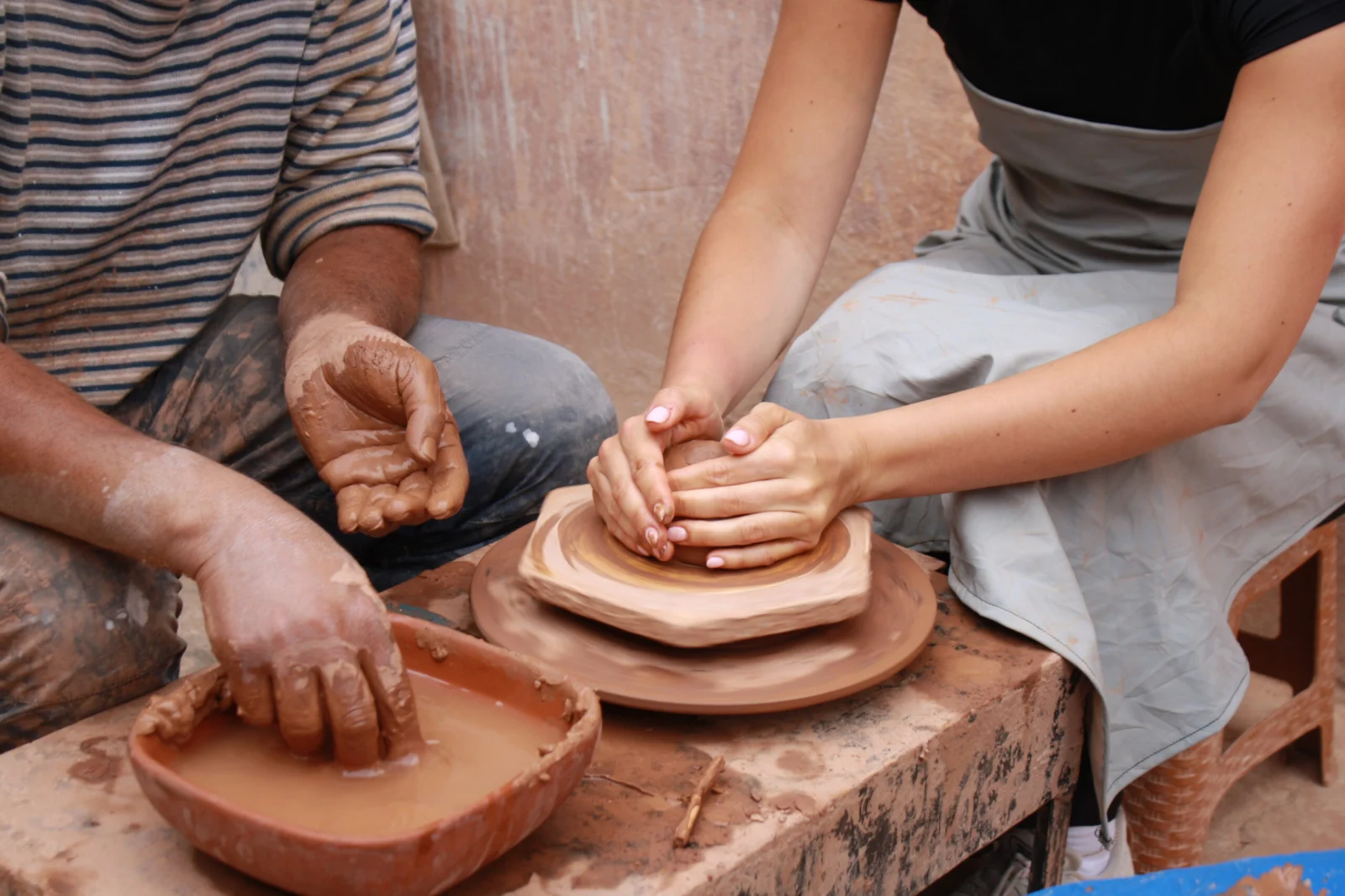 Pottery workshop Agadir with a local artisan guiding a visitor's hands at the wheel
