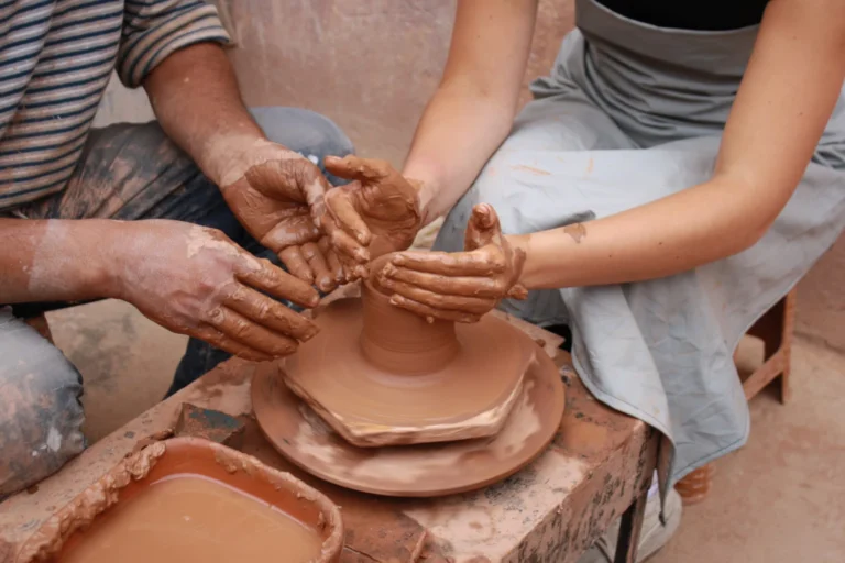 Artisan helping a visitor center clay on the pottery wheel