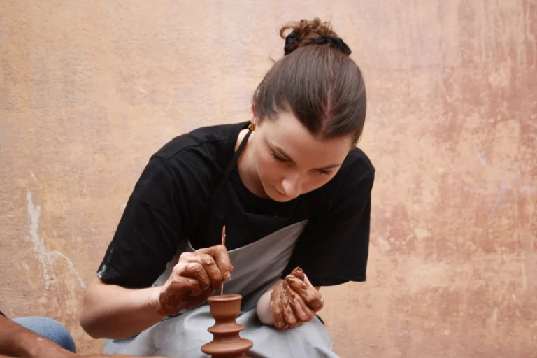 Visitor shaping a small clay vase on a pottery wheel