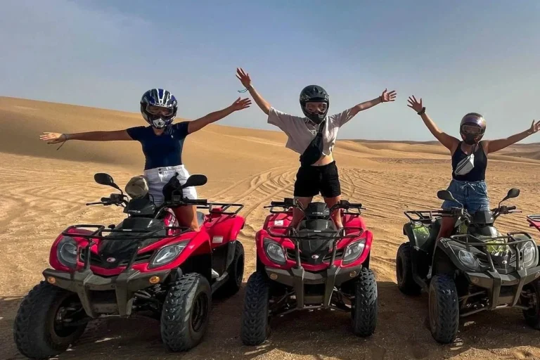 Riders on quad bikes celebrating together on sand dunes near Agadir