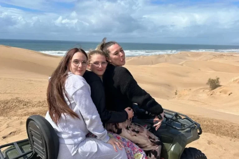 Group of women posing on a quad bike with the Agadir coastline behind