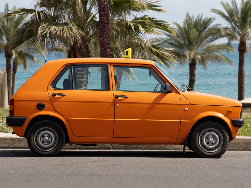 A small orange city taxi parked on a sunny street near the Agadir seafront