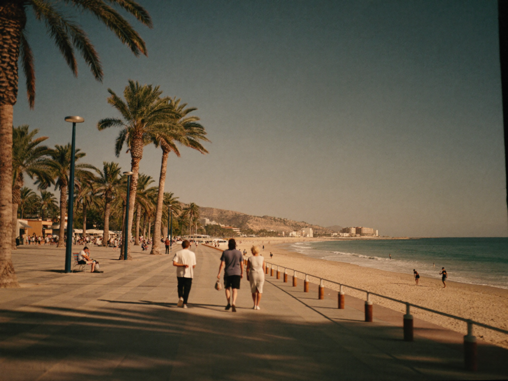 Travelers walking along a wide palm-lined beachfront promenade in Agadir in the late afternoon
